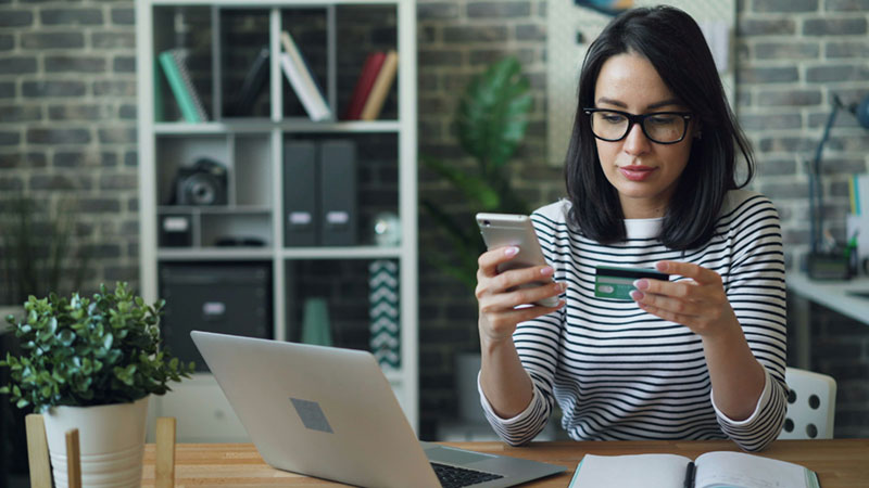 A woman does banking at her desk. GICs and GIOs are a secured form of investment we offer.