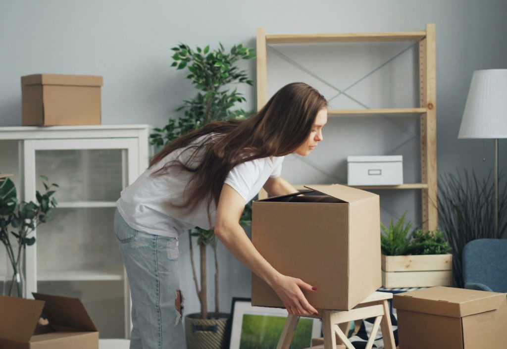 A young person packing boxes for a move. If you're saving for a house or other major purchase, a TFSA might be the best investment type for you.
