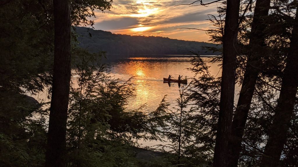 We offer life insurance policies. An image of two people canoeing on a placid lake.